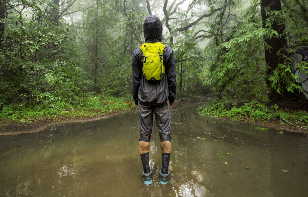 En person står i skogen med ryggen vänd mot kameran och med den nya ryggsäcken på ryggen.